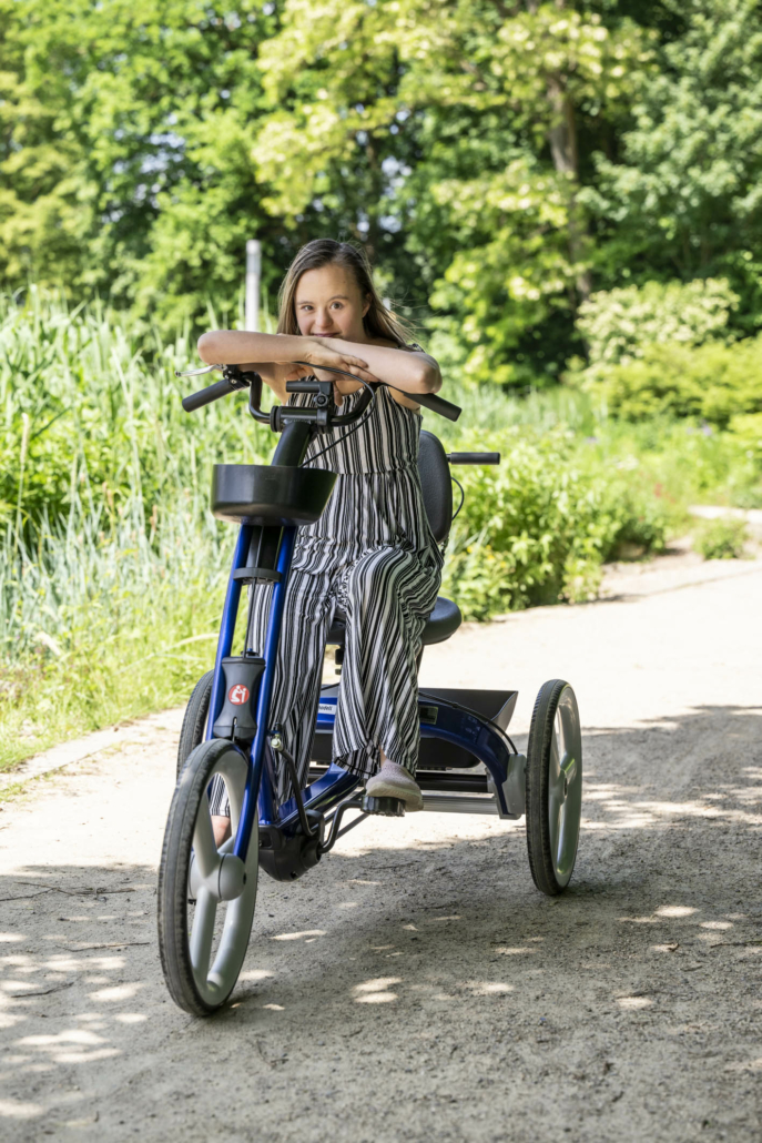 Kind mit Behinderung fährt draußen optimiertes Dreirad