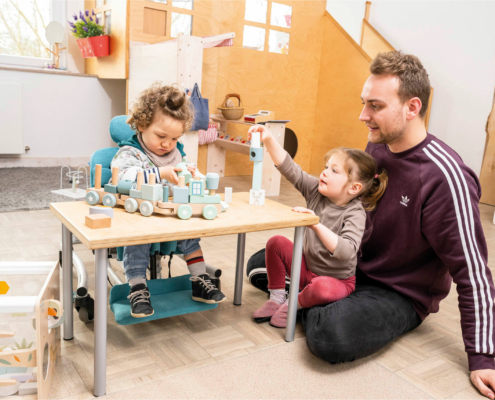 Kind mit Behinderung spielt im Therapiestuhl von Schuchmann