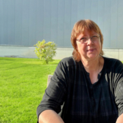 Sigrid Hirte, Teamleiterin der Polsterei und Näherei bei Schuchmann sitzt draußen am Tisch vor einer Rasenfläche
