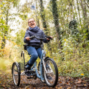 Ein Mädchen mit Behinderung sitzt auf dem momo dreirad. Einem Fahrrad für Kinder mit Behinderung.