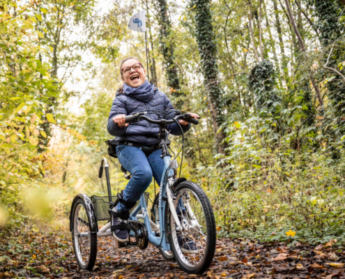 Ein Mädchen mit Behinderung sitzt auf dem momo dreirad. Einem Fahrrad für Kinder mit Behinderung.
